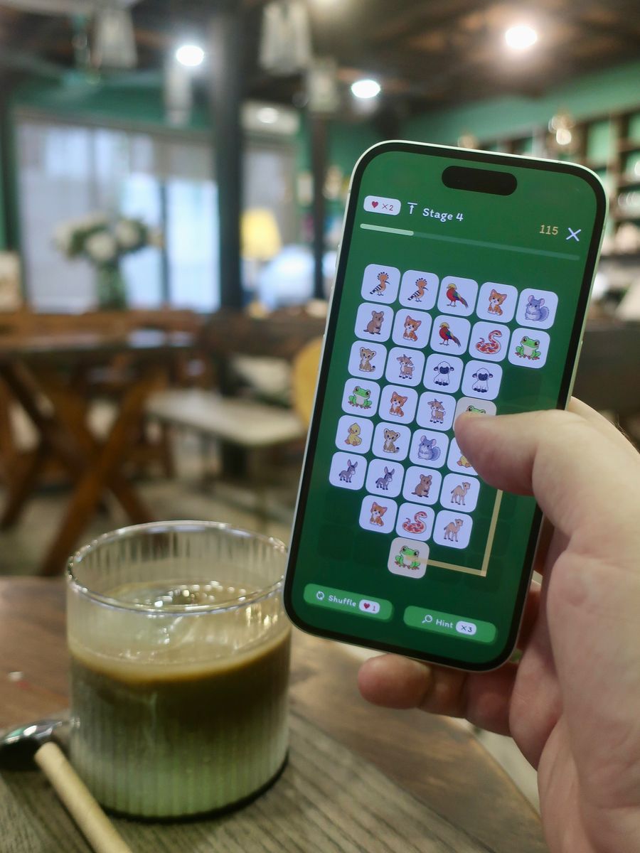 Linking two frogs on a farm-animal board in a cosy café, with an iced drink on the table.