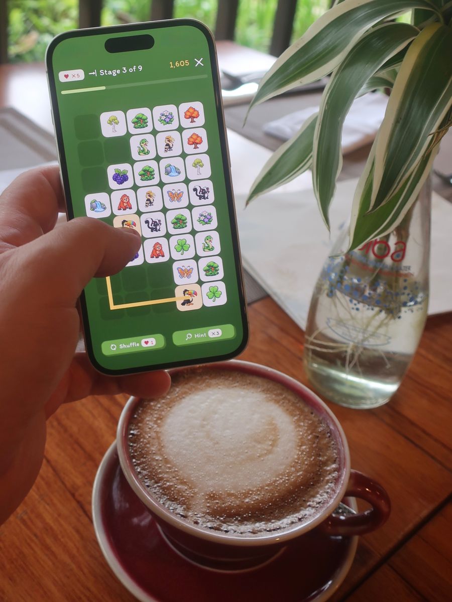 A forest-themed board, stage 3 of 9, held over a cappuccino.